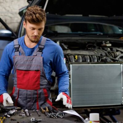 Mechanik pracuje przy stole warsztatowym przygotowując się do naprawy klimatyzacji samochodowej.