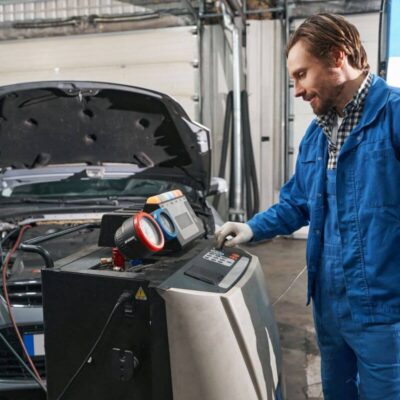 Mechanik przeprowadza naprawę klimatyzacji samochodowych przy użyciu specjalistycznego sprzętu.
