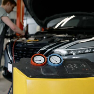 Mechanik w warsztacie dokonuje naprawy klimatyzacji samochodowych przy użyciu specjalistycznego sprzętu.