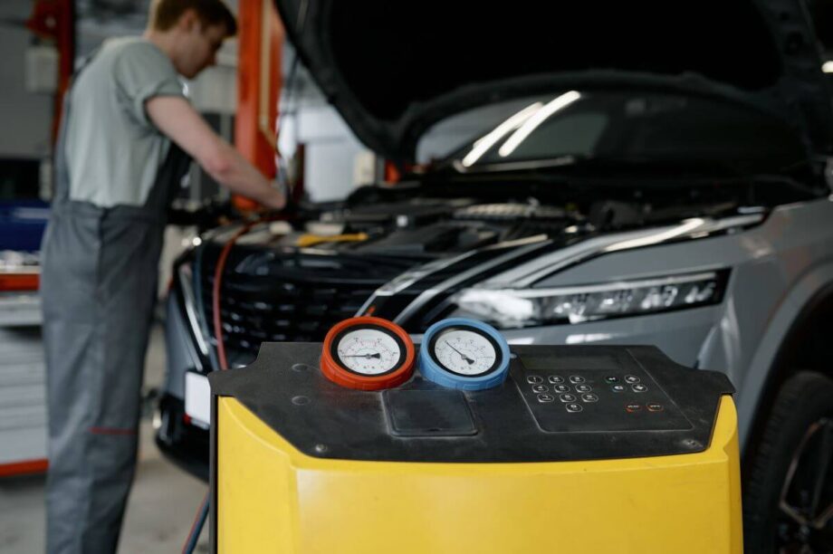 Mechanik w warsztacie dokonuje naprawy klimatyzacji samochodowych przy użyciu specjalistycznego sprzętu.