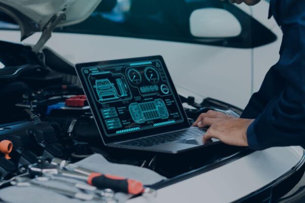 Mechanik korzysta z laptopa, aby przeprowadzić diagnostykę komputerową silników w samochodzie.