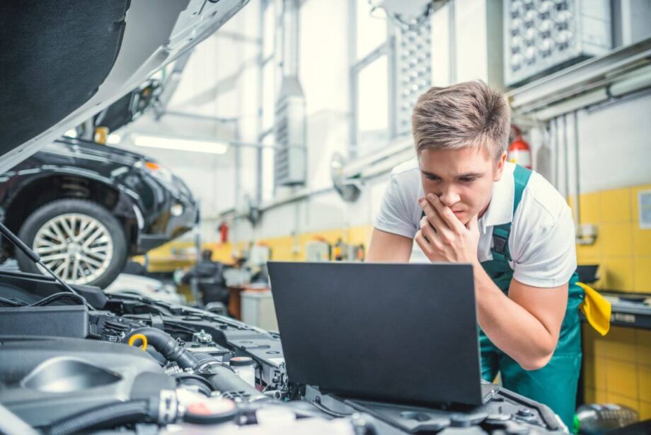 Mechanik wykonuje diagnostykę komputerową silnika w warsztacie samochodowym.