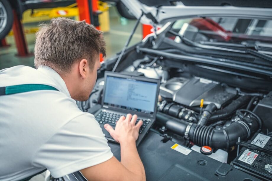 Mechanik wykonuje diagnostykę silnika za pomocą laptopa.