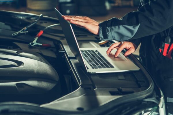 Mechanik przeprowadza diagnostykę silnika przy użyciu laptopa.