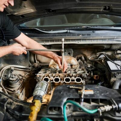 Mechanika samochodowa: mężczyzna pracuje przy silniku samochodu.