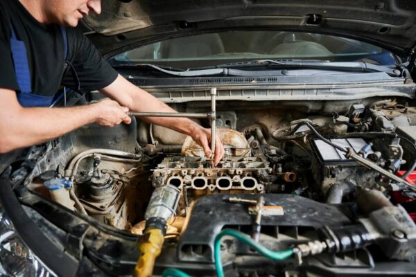 Mechanika samochodowa: mężczyzna pracuje przy silniku samochodu.