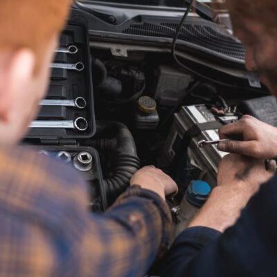 Dwóch mężczyzn zajmuje się naprawą silników, korzystając z kluczy.