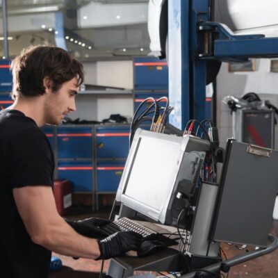 Mechanik przeprowadza diagnostykę komputerową silników w warsztacie samochodowym.