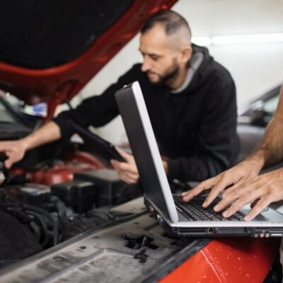 Dwóch mechaników wykonuje diagnostykę komputerową silników przy użyciu laptopa.