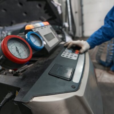 Technik w warsztacie wykonuje naprawę klimatyzacji samochodowych przy użyciu specjalistycznego sprzętu.